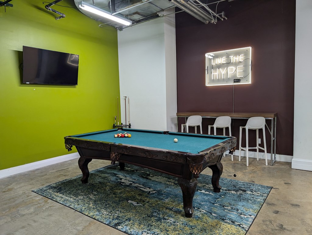 a pool table in a room with a tv and a green wall