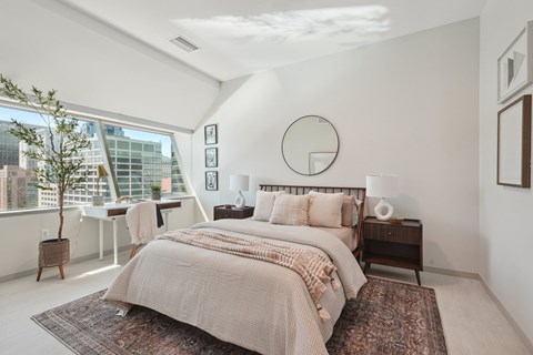 A bedroom with a large bed and a view of the city.