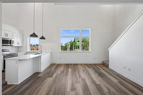 A kitchen with white cabinets and a window overlooking a green landscape.