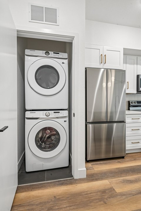A white washer and dryer are stacked in a small space.