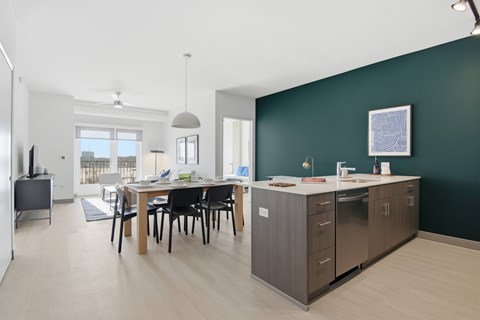 A modern kitchen with dark green walls and a dining table with chairs.