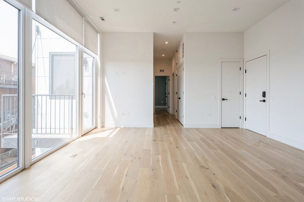 A spacious room with wooden flooring and white walls.