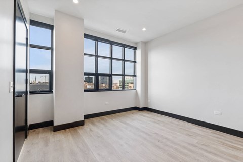 an empty living room with a large window and wood flooring