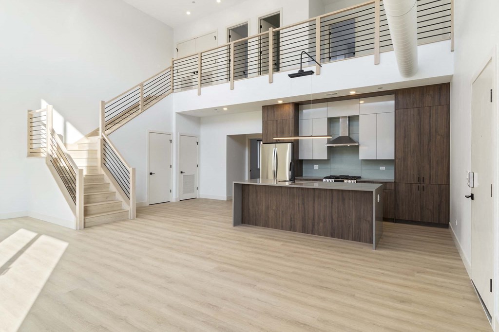 a large living room with a kitchen and a staircase