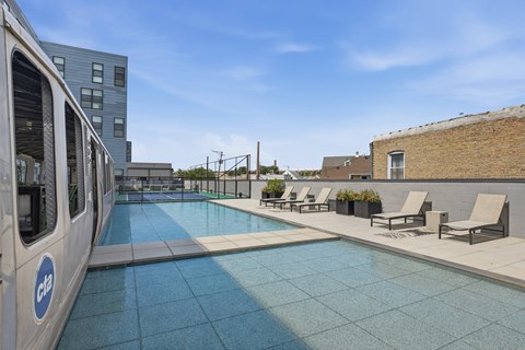 A pool area with a train on the left and chairs on the right.