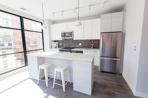 a white kitchen with a large island and white stools