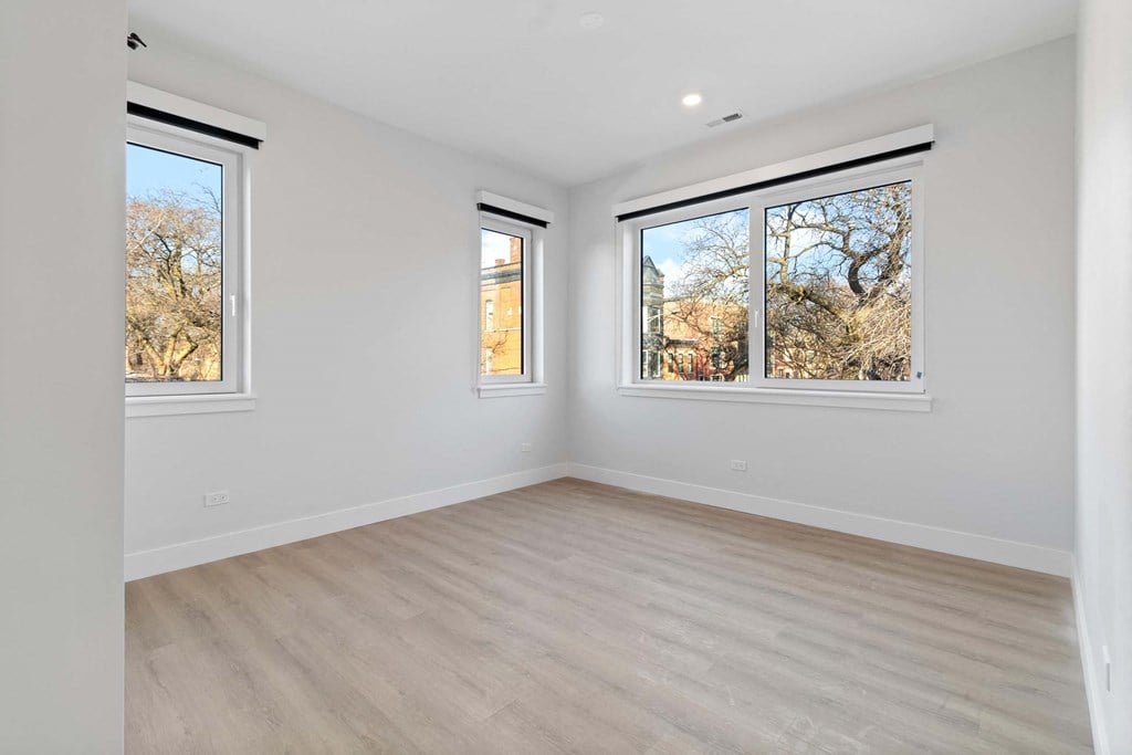 a living room with wood floors and three windows