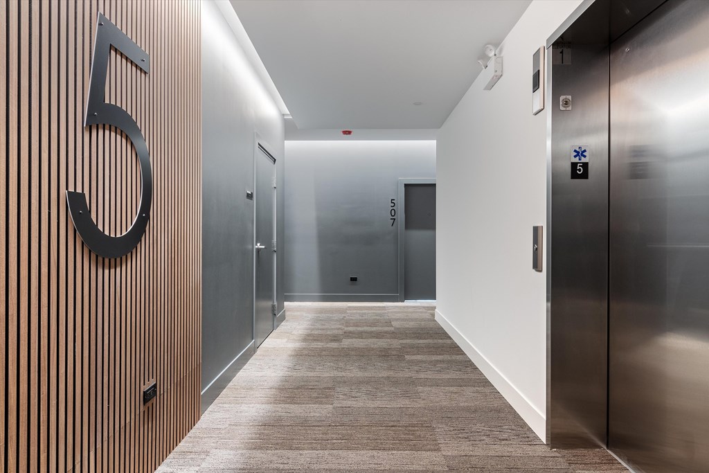A hallway with a number 5 on the wall and elevators on the right.