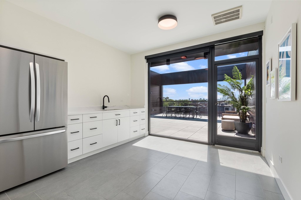 A kitchen with a refrigerator, drawers, and a sliding glass door leading to a balcony.