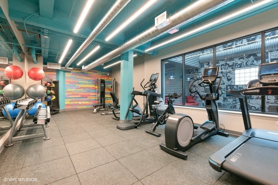 a gym with various machines and weights in a building with a large window