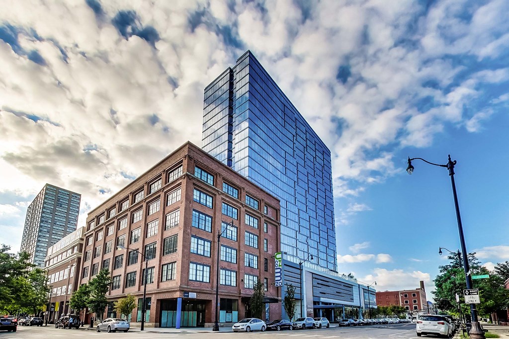 a tall building on a city street under a cloudy sky