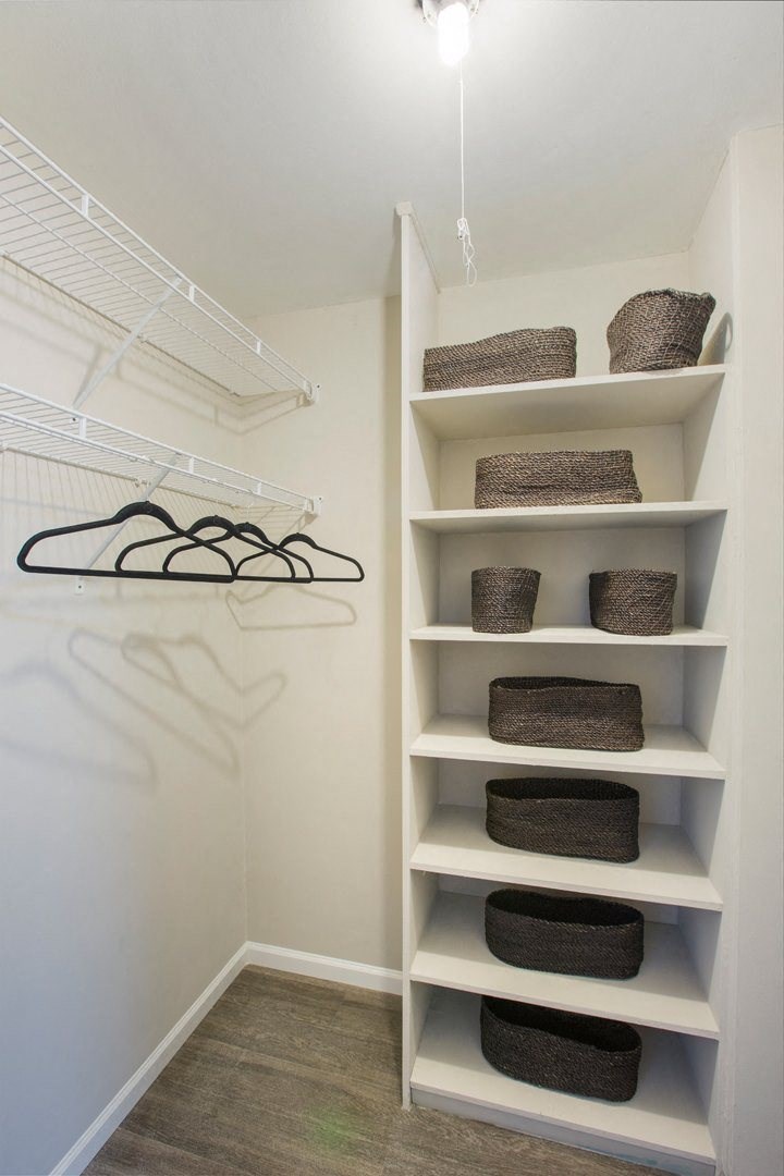 a walk in closet with shelves and baskets