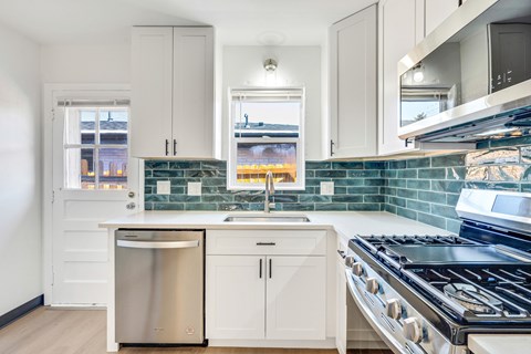 A kitchen with white cabinets and a stainless steel dishwasher.