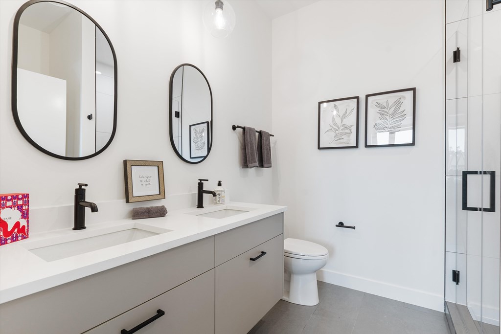 A bathroom with a toilet, sink, and mirrors.
