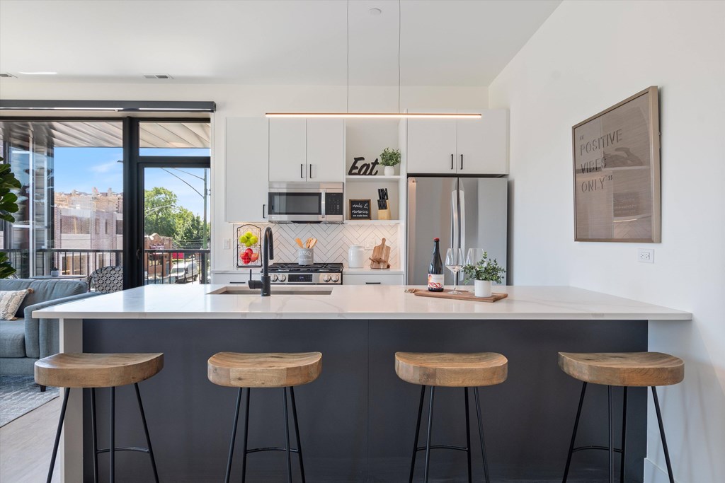 A modern kitchen with a bar stool in front of the island.