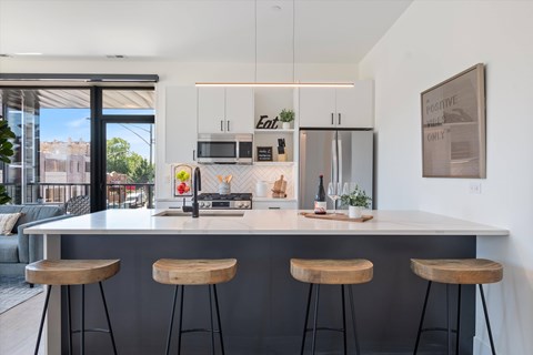 A modern kitchen with a bar stool in front of the island.