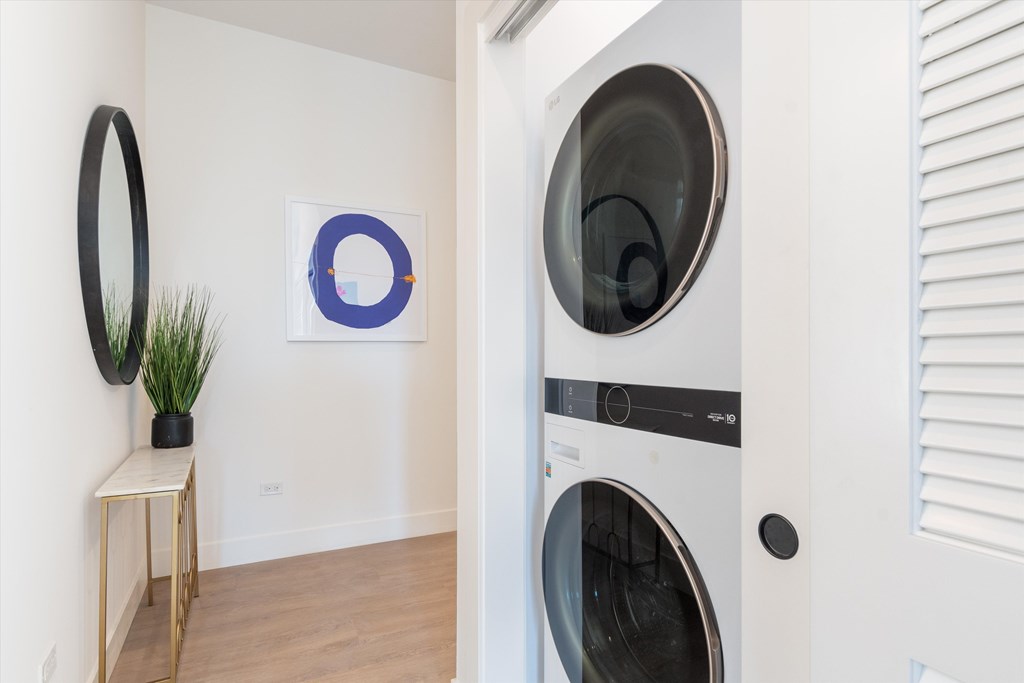A modern laundry room with a washing machine and a small table with a potted plant.