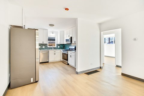A kitchen with white cabinets and a wooden floor.