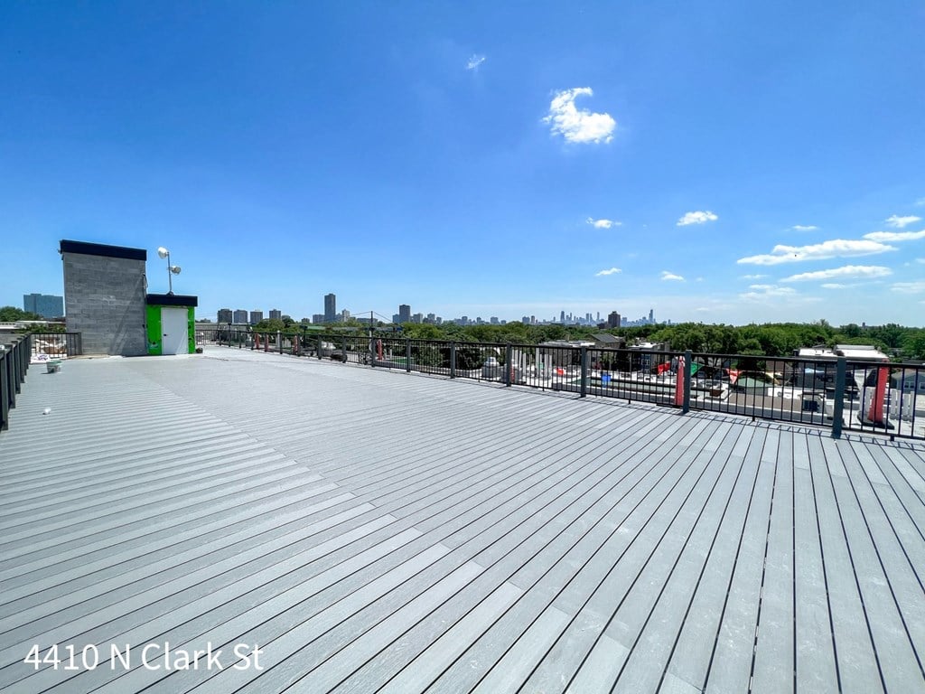 A rooftop with a wooden deck and a green structure in the distance.