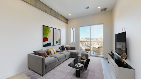 A living room with a grey couch and a painting on the wall.