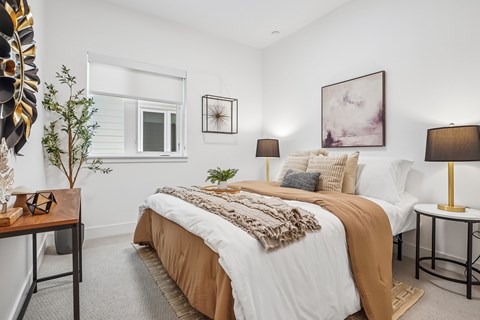 A bedroom with a large bed and a small table with a lamp.