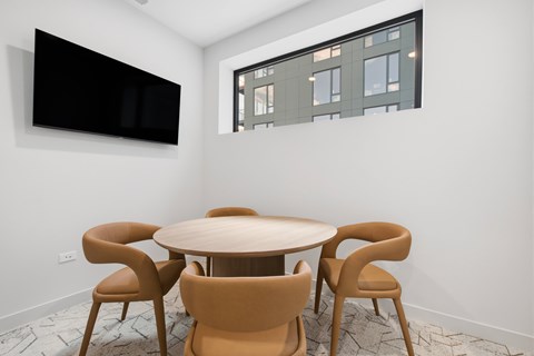 A conference room with a table and chairs and a television on the wall.