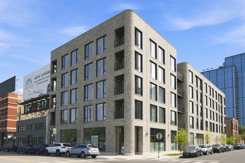 A building with a sign that says "NOW LEASING" is in front of a blue sky.