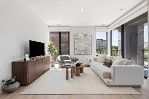 A modern living room with a white sofa, wooden coffee table, and a flat-screen TV.