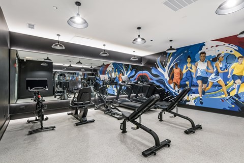 A gym with a row of treadmills and a colorful mural on the wall.