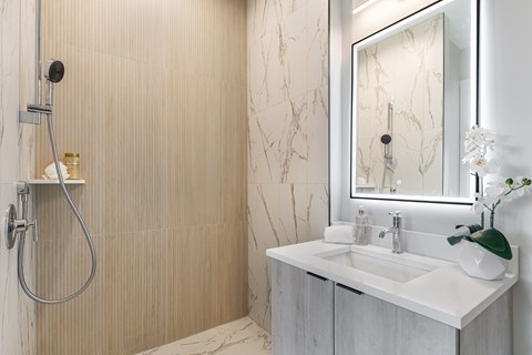 A bathroom with a marble patterned shower wall and a white sink vanity.