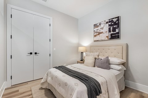 A bedroom with a bed, pillows, a lamp, and a picture on the wall.