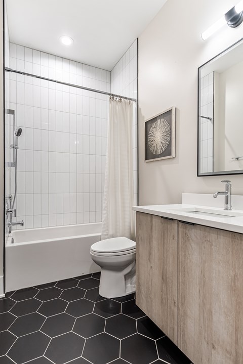 A white toilet sits in a bathroom with a black and white tiled floor.