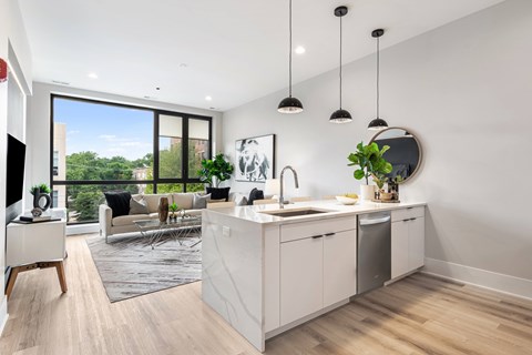 A modern kitchen with a large window overlooking a green area.