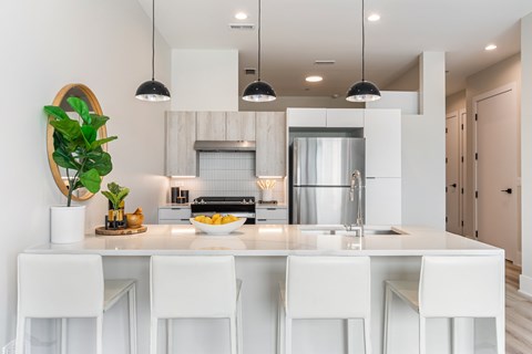 A modern kitchen with white chairs and a white counter.