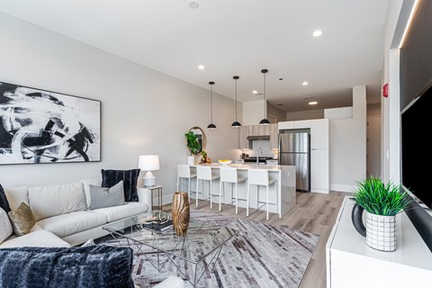 A modern living room with a white sofa, a glass coffee table, and a large abstract painting on the wall.