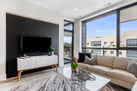 A modern living room with a large flat screen TV on a white cabinet.