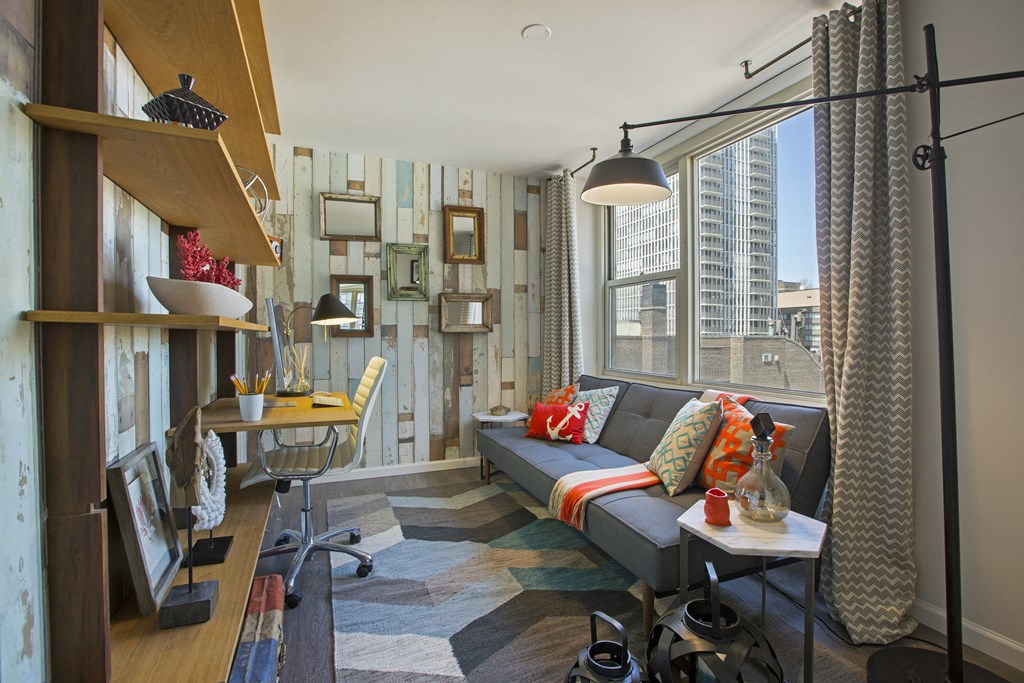 a small living room with a couch and a desk and a window