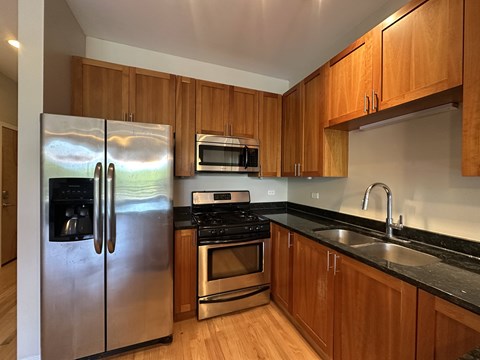 A kitchen with wooden cabinets and a stainless steel refrigerator.