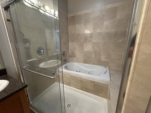 A bathroom with a glass shower door and a white bathtub.