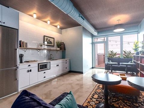 A modern kitchen with a refrigerator, oven, and a dining table with chairs.