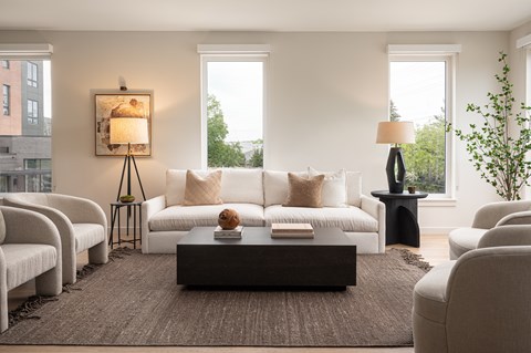 A living room with a white couch, a brown rug, and a painting on the wall.