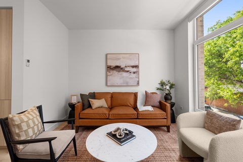 A living room with a brown couch, a white coffee table, and a painting on the wall.