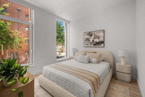 A bedroom with a large bed and a potted plant.