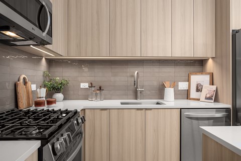 A modern kitchen with a black stove top oven and wooden cabinets.