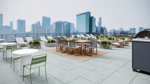 A rooftop patio with a table and chairs overlooking a city skyline.