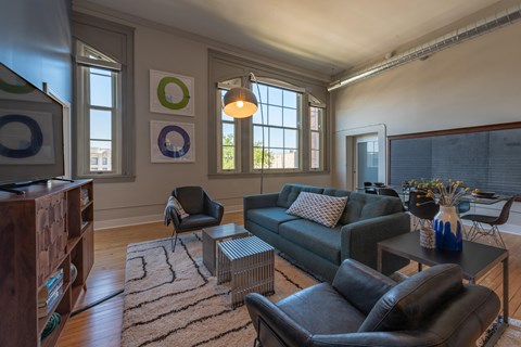 A living room with a grey couch, a black chair, a coffee table, and a rug.