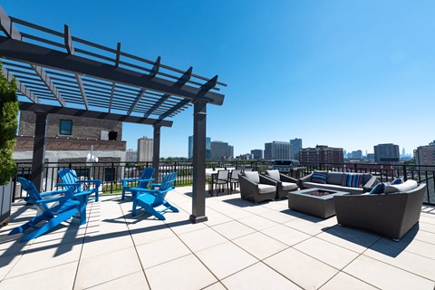 A rooftop patio with blue chairs and a white couch.