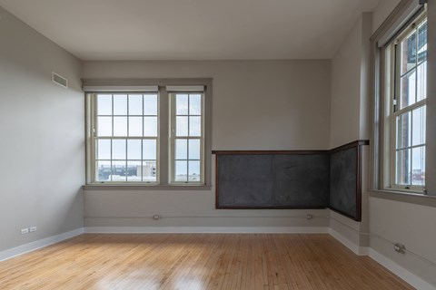A room with a large blackboard on the wall and wooden flooring.