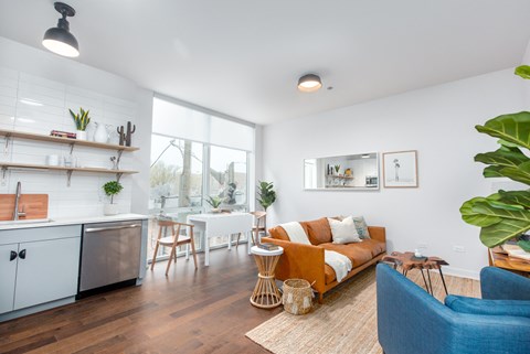 A modern living room with a kitchen area in the background.