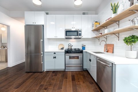 A modern kitchen with stainless steel appliances and wooden floors.